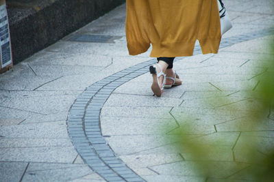 Low section of woman walking on footpath