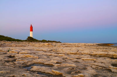 Lighthouse on against sky during sunset