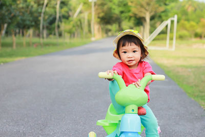 Portrait of cute girl cycling on footpath