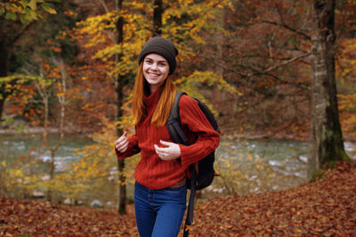 Portrait of smiling young woman in forest during autumn