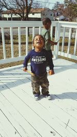 Boy playing with arms outstretched standing against trees