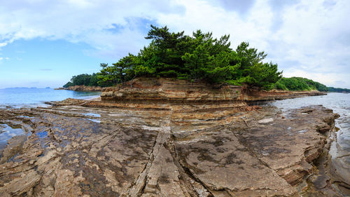 Panoramic view of a rocky coastline on a remote island against cloudy sky