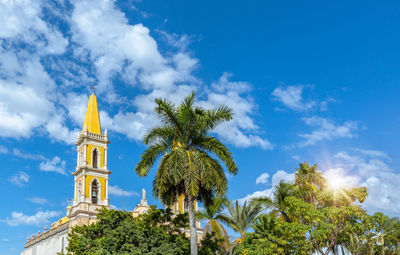 Low angle view of palm trees and building against sky