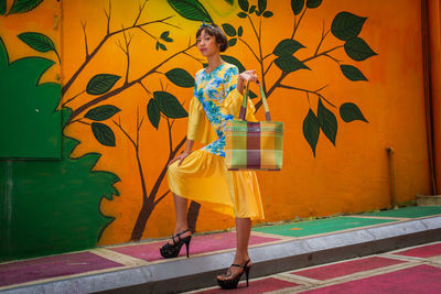 Portrait of female model standing against patterned wall