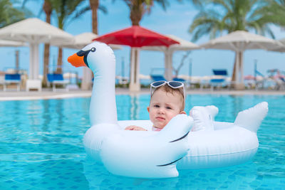 Cute girl with inflatable ring swimming in pool