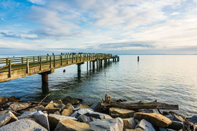 Pier over sea against cloudy sky