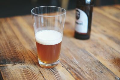 Close-up of beer in glass by bottle on table