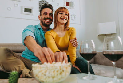 Couple watching tv while sitting on sofa at home