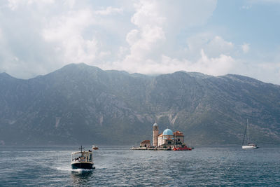 Sailboat sailing on sea against mountains