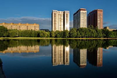 Reflection of buildings in lake against blue sky