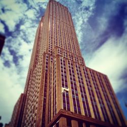 Low angle view of skyscrapers against cloudy sky