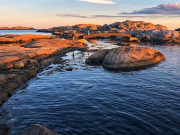 Rock formation in sea against sky during sunset