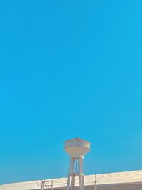 Low angle view of water tower against clear blue sky