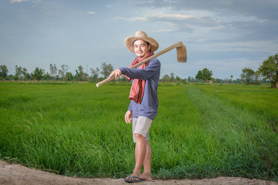 Full length portrait of smiling woman standing on field