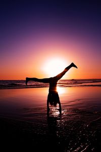 Silhouette woman on beach against sky during sunset