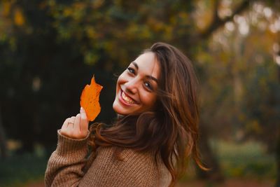 Portrait of smiling young woman standing during autumn