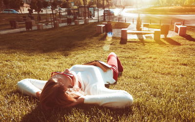 Woman lying on grassy field in sunny day