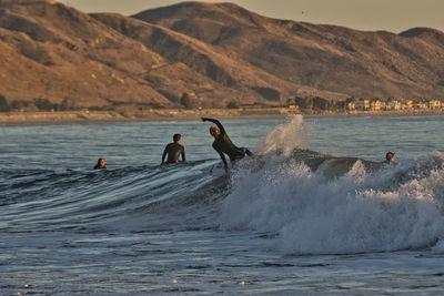 People on sea by mountain