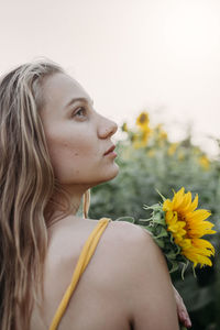 Portrait of woman with yellow flowers against blurred background