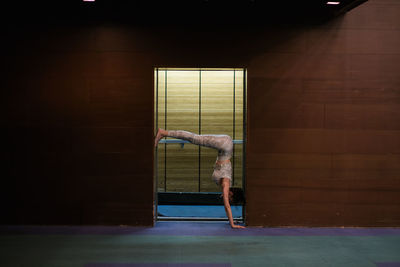 Side view of woman doing yoga at doorway