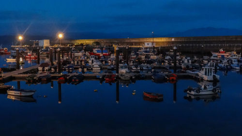 Sailboats moored on harbor in city at night