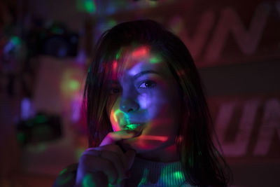 Close-up portrait of young woman with long hair in illuminated room at night