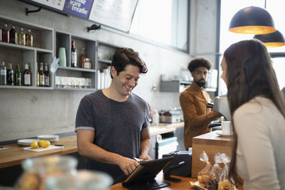 Smiling barista using tablet pc at counter in cafe