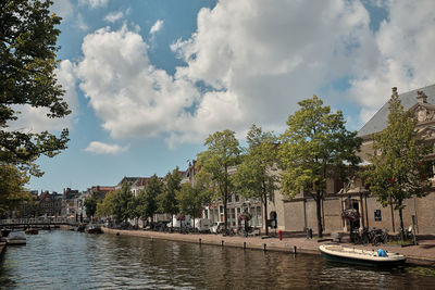 Scenic view of river amidst trees and buildings against sky