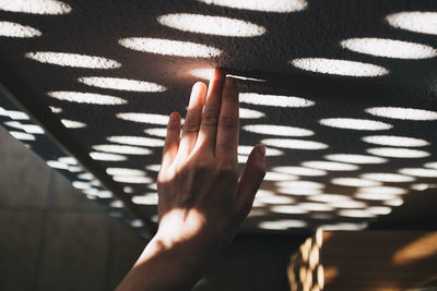 Hand touching pattern made by sunlight on wall