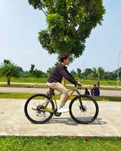 Side view of man riding bicycle on field