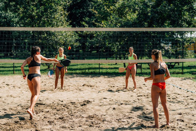 Female friends playing beach tennis