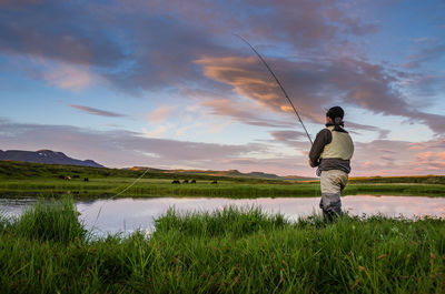 Rear view of man fishing on lake