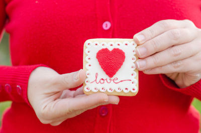 Close-up midsection of woman holding cookie with heart shape