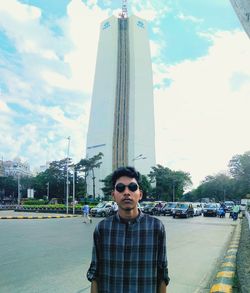 Young man standing by road against sky