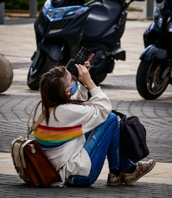 Rear view of woman photographing with mobile phone