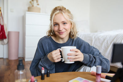 Portrait of young woman using mobile phone while sitting at home