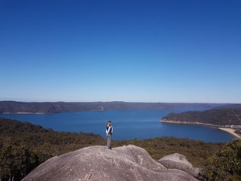 Man standing by sea against clear blue sky