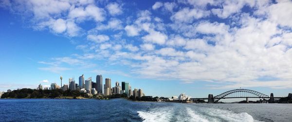 Sydney harbor bridge and city skyline against cloudy sky