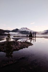 Scenic view of lake by snowcapped mountains against sky