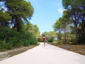 Rear view of man walking on footpath by road