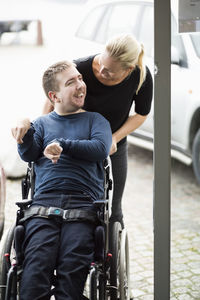 Caretaker talking to disabled man on wheelchair outdoors