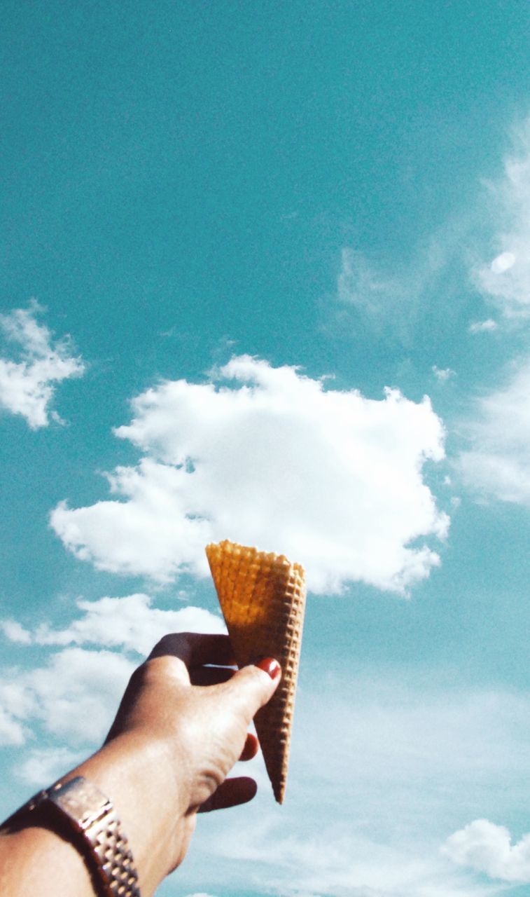 MIDSECTION OF PERSON HOLDING FOOD AGAINST SKY