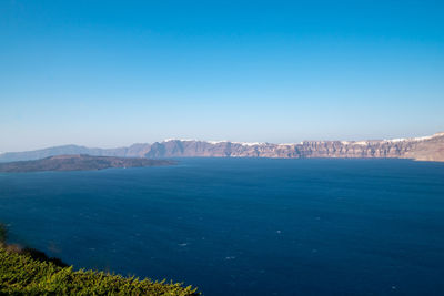 Scenic view of sea and mountains against clear blue sky