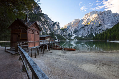 Built structure by lake and mountains against sky