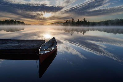 Boat in lake against sky during sunset