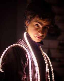 Portrait of man wearing string light while standing at home