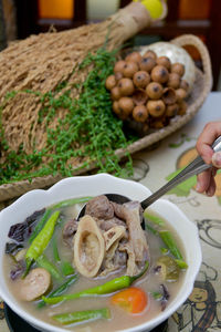 Midsection of person holding rice in bowl on table