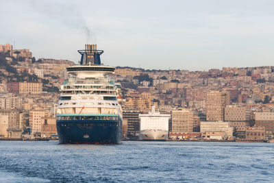 Buildings and cruise ships by sea against sky in city