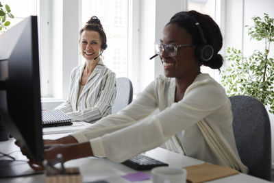 Two women wearing headsets and sitting at desk in office