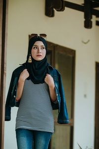 Portrait of young woman standing at home